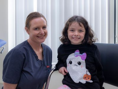 A healthcare worker beside a young girl sitting on a couch.