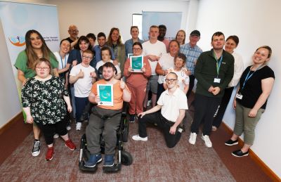 Large group of staff and service users from St Michael's House.  2 service users are holing copies of the Easy Read version of the HSE Consent Policy. 