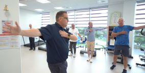 Group if men in a gym setting doing arm stretching exercises