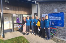 7 healthcare workers standing outside the door of a healthcare building.