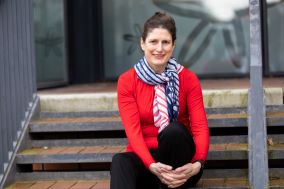  Nóirín Russell is wearing a red jumper and is sitting on a staircase